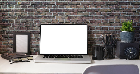 Fototapeta premium Computer laptop with empty screen, coffee cup, potted plant and stationery on white table.