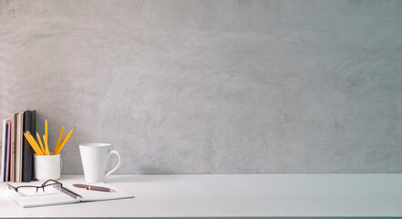 Minimal workplace with coffee cup, glasses, notebook and pencil holder on white table. Copy space for your text.