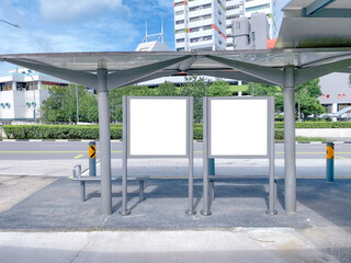Two bus stop blank advertising mock ups at empty bus stop shelter by main road. Out-of-home OOH...