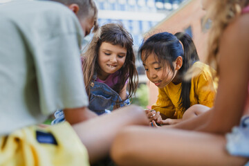 Happy kids playing and talking together in city park, during summer day.