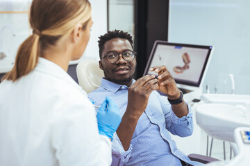 Young good looking man having dental treatment at dentist's office. African guy in dentist chair looking with trust at his doctor, close up. Man having teeth examined at dentists.