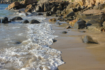waves reaching a beach full of rocks