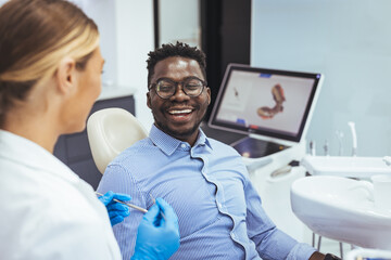Young man patient having dental treatment at dentist's office. Female dentist working on patient's teeth. Man having teeth examined at dentists. Overview of dental caries prevention