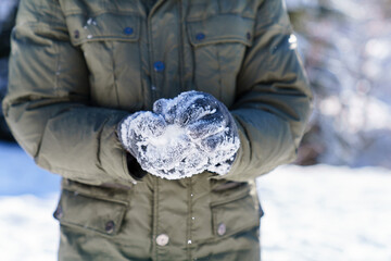 Man making snowballs in winter. Close up of male hands in snowy gloves. Playing in snow and having fun on nature. Family outdoors activities on Christmas holidays. Authentic lifestyle moment