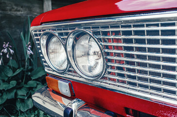 Headlights of a red car close-up. The front of an old red Lada car. Blurred background.