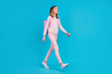 Full length photo of charming pretty small girl wear dotted shirt backpack walking empty space...