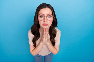 Photo of young sad emotion female in spectacles asking for help donation save me isolated on blue...