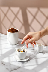 Woman stir coffee with coffee spoon. Coffee cup, hot drink in a mug. Beige and marble background...