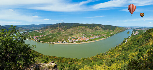 Hot air balloons in the sky over the Danube river in the Wachau valley.