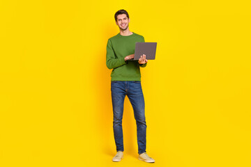 Photo of cute charming guy dressed green pullover typing modern device isolated yellow color background