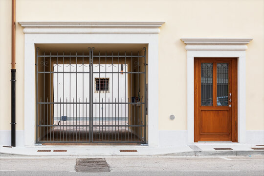 Porta di entrata di casa e passo carrabile su facciata gialla  di edificio ristrutturato. Centro storico di piccola citt&agrave;.
