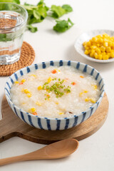 Delicious rice porridge congee with corn kernel and vegetables on white table background.