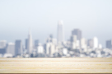 Empty wooden table top with beautiful blurry skyscrapers at daytime on background, mock up