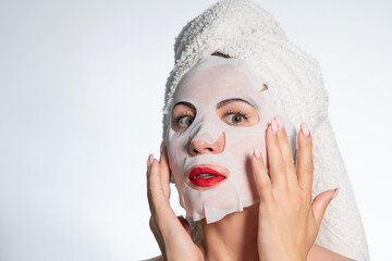 Woman with a towel on her hair and a mask on her face, skin and hair care.