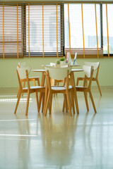 Dining table with set in modern home, White sunlight shines through the Venetian curtains on the windows.