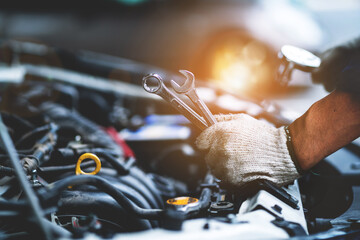 Close-up photo of a car mechanic working on a car engine in a mechanics repair service garage. A...