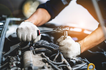 Close-up photo of a car mechanic working on a car engine in a mechanics repair service garage. A...