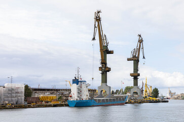 crane unloading big ship in shipyard