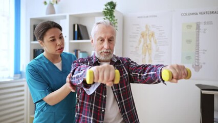 Retired man training with dumbbells in rehabilitation center, body recovery