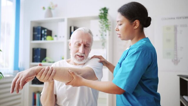 African American doctor examining patient with hand injury, physiotherapy