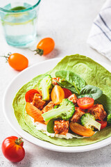 Open vegan tortilla wrap with broccoli, tofu and tomatoes. Vegetarian recipe, comfort food, plant-based concept.