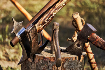 Hatchets and axes are stuck in a rustic wooden block