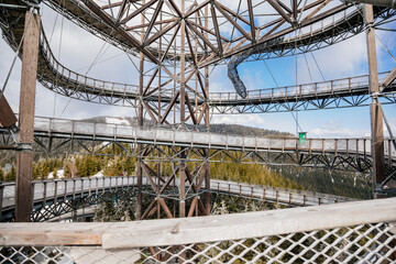 Obraz premium Dolni Morava, Czech Republic, 16 April 2022: Path in the clouds, tourist attraction with spiral platform to observation tower, landscape with forest and sky on mountains, Skywalk with snow
