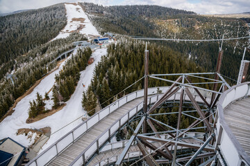 Fototapeta premium Dolni Morava, Czech Republic, 16 April 2022: Path in the clouds, tourist attraction with spiral platform to observation tower, landscape with forest and sky on mountains, Skywalk