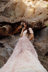 Fashionable young model in boho style dress on a background of rocks. Female beauty and style concept.