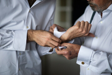 older man helping to fasten his son's cufflinks on his wedding day