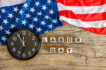 US American flag with wooden cubes with word Labor day and clock on old wooden background. Labor day celebration. 