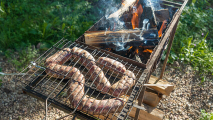 Tasty homemade sausage made of beaver meat cooking on grill. Beaver meat sausages are cooked on coals.