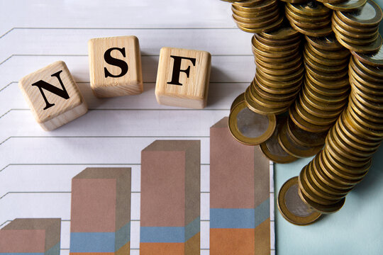 NSF - acronym on a green sheet on the background of a graph, pencils and coins