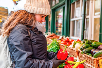 Young woman buying vegetable on stall at the market