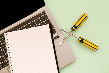 yellow screwdrivers, note book and computer on green background