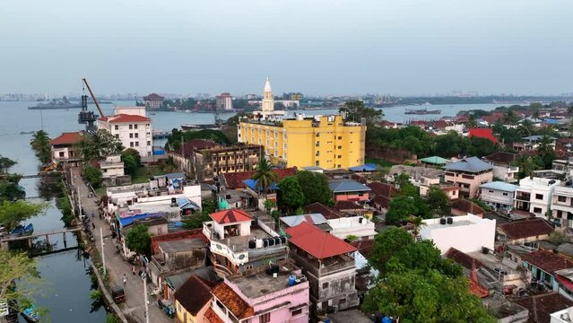 Aerial Shot Of Clock Tower Amidst Houses In City By Lake, Drone Flying Forward Over Canal - Kochi, India