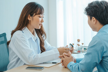 Obraz premium Female doctor and young male patient while consult and .explain. Doctor and patient sitting together at table in examination room.