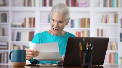 Fototapeta premium Stressed senior woman holding letter troubled with domestic bills, bad news.