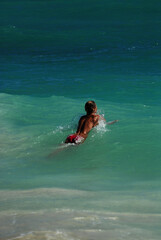 A young topless woman swims in the Caribbean Sea on a sunny day during her summer vacation in Mexico