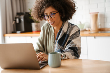 African american young woman with afro hairstyle using laptop at home