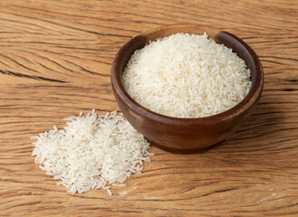 Fototapeta na wymiar Raw white rice in a bowl over wooden table