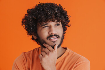 Young indian handsome thoughtful man looking aside touching his chin