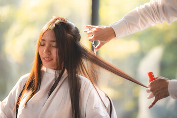 Young woman getting hair cut and hair styling done in modern salon by male professional barber