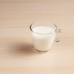 Transparent cup with milk on a wooden table. Delicious Drink