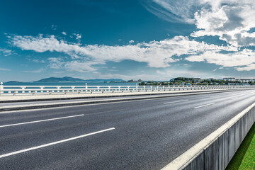 Asphalt road and river with mountain nature landscape under blue sky