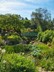 Fototapeta na wymiar Green Bridge Crossing Beautiful Flower Garden