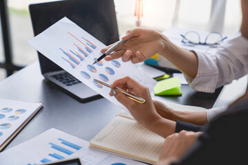 Teamwork process. Two business women calculating a valuation in the workplace. laptop on the table, typing keyboard, analysis of earnings, analyzing graph plans