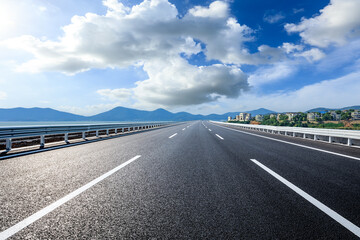 Fototapeta premium Asphalt road and river with mountain nature landscape under blue sky