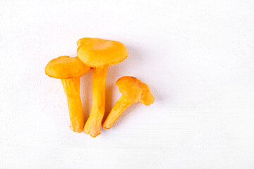 Three chanterelle mushrooms on white table. Flat lay with the ingredient. Copy space © kcuxen