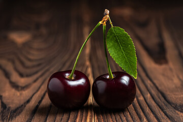 Sweet cherries with cherry leaf on a wooden background.